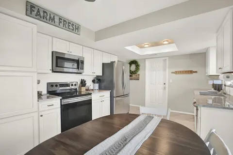 a kitchen with stainless steel appliances granite countertop a refrigerator a stove top oven a sink dishwasher and white cabinets with wooden floor