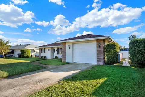 a view of a white house next to a yard with big trees
