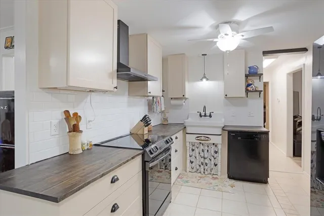 a kitchen with a sink dishwasher a stove a refrigerator and white cabinets