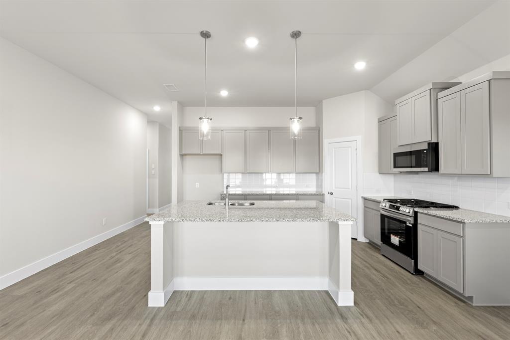 2372 Bell Way Forney, TX 75126 - Photo 13 of 39 a large white kitchen with kitchen island a sink wooden floor and stainless steel appliances