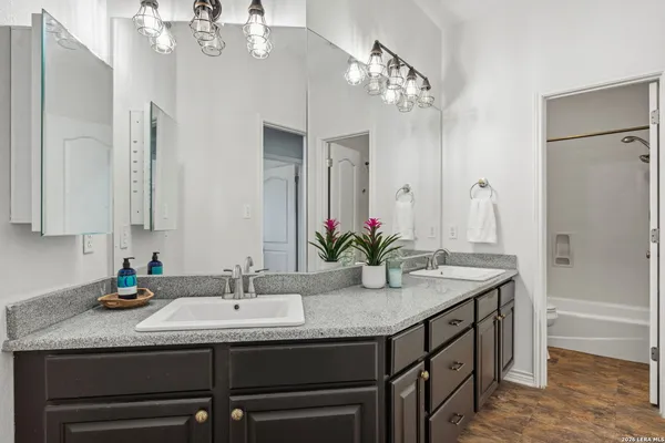 a bathroom with a granite countertop sink a mirror and a shower
