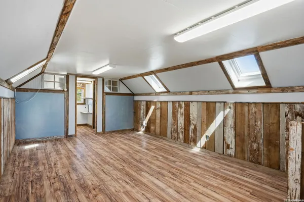 a view of an empty room with wooden floor and stairs
