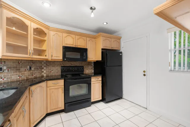 a kitchen with granite countertop a refrigerator and a stove top oven