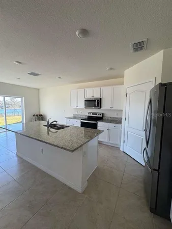 a large kitchen with granite countertop a refrigerator oven a sink and dishwasher