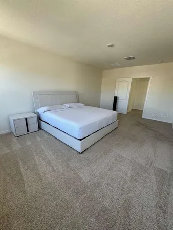 a spacious bedroom with a bed and a lamp on desk