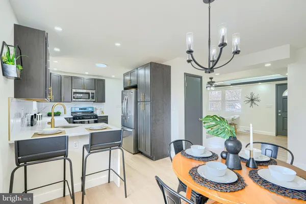 a kitchen with stainless steel appliances a refrigerator a sink a stove a dining table and chairs with wooden floor