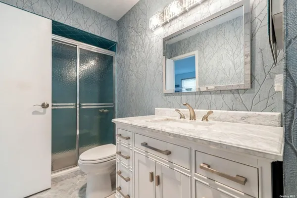 a bathroom with a granite countertop sink toilet mirror and a shower