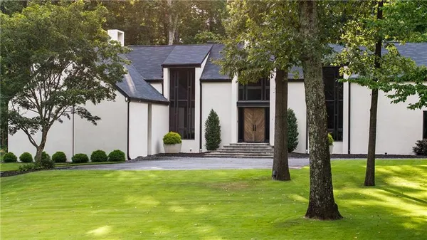 a view of house with patio outdoor seating and covered with trees