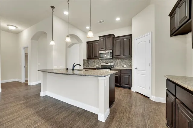 a large kitchen with stainless steel appliances granite countertop a sink a stove and a refrigerator