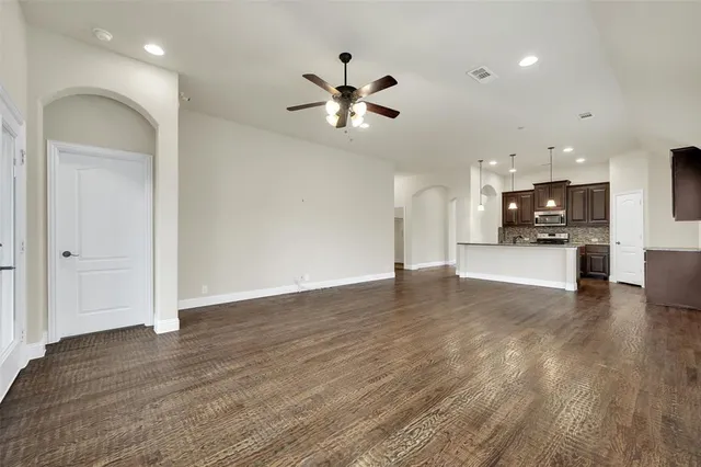 a view of an empty room with wooden floor and windows