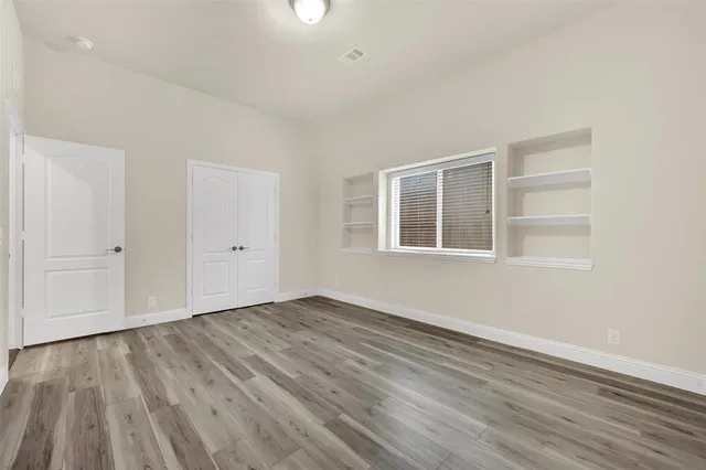 an empty room with wooden floor and windows
