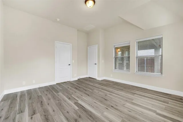 an empty room with wooden floor fireplace and windows