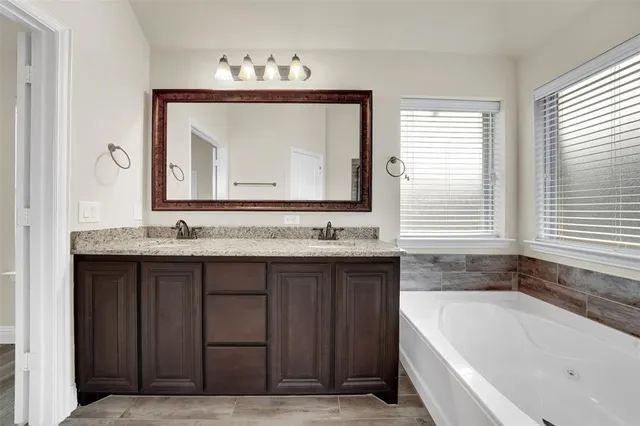 a bathroom with a granite countertop bathtub a sink and a window