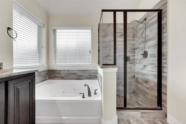a bathroom with a granite countertop bathtub a sink and a window
