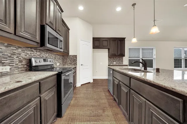 a kitchen with stainless steel appliances granite countertop a sink a stove oven a counter space and cabinets