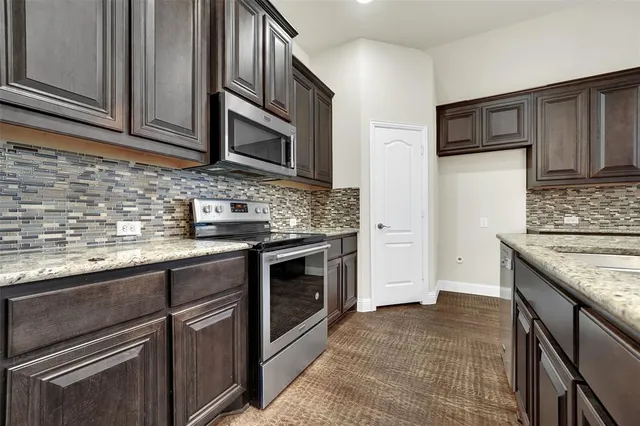 a kitchen with stainless steel appliances granite countertop a stove microwave and cabinets