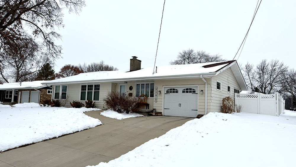 a front view of a house with a yard covered in snow