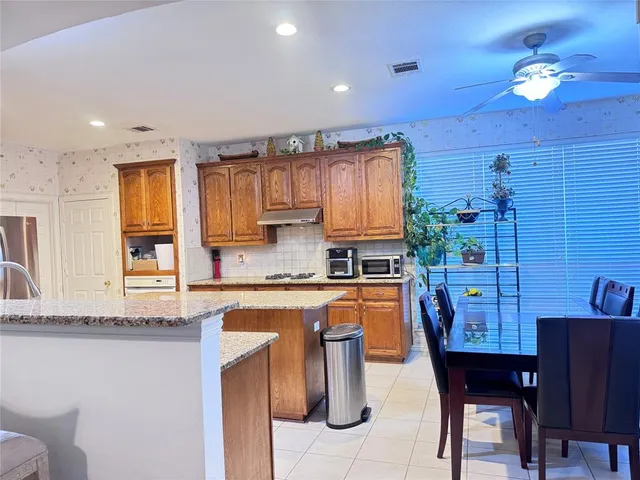 a kitchen with stainless steel appliances granite countertop wooden cabinets a dining table and chairs