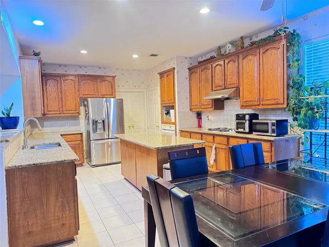 a kitchen with stainless steel appliances granite countertop a stove a sink dishwasher a refrigerator with white cabinets and wooden floor