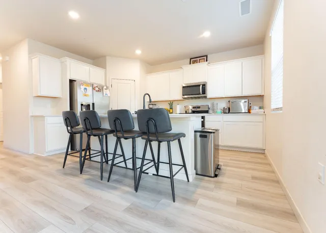 a kitchen with stainless steel appliances kitchen island granite countertop a table chairs microwave and sink