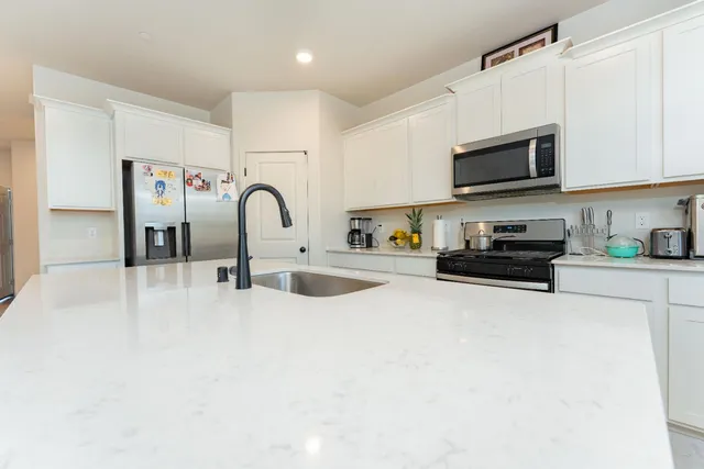 a kitchen with stainless steel appliances granite countertop a stove a sink and a microwave