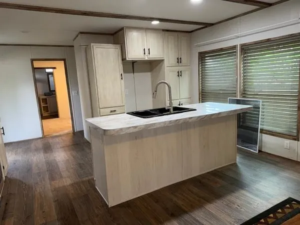a kitchen with kitchen island granite countertop a sink cabinets and wooden floor