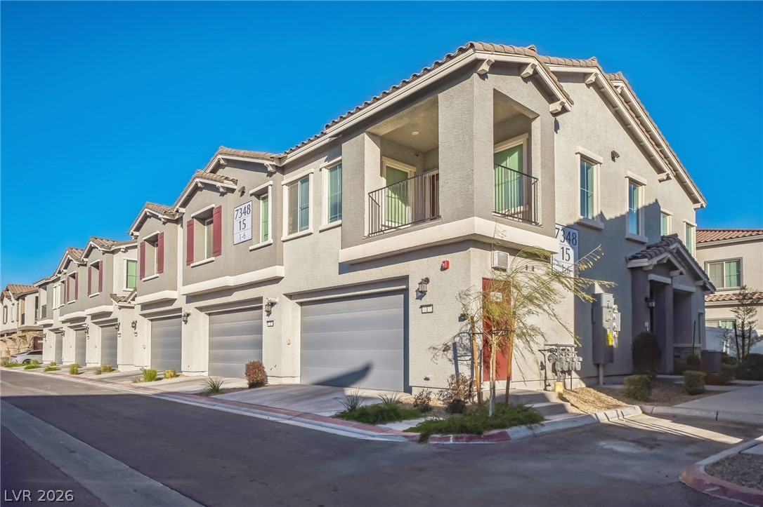Rows of contemporary townhomes feature individual garages and second-story balconies, creating a structured streetscape.