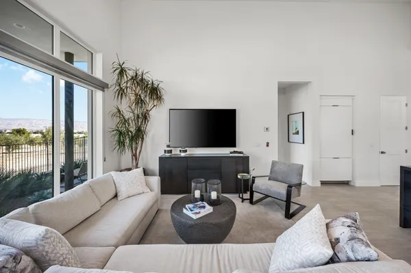 a living room with furniture a flat screen tv and a large window