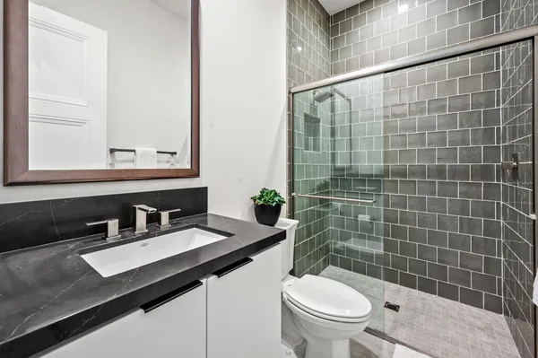 a bathroom with a sink a toilet a mirror and shower