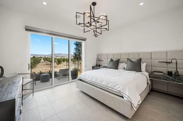 a spacious bedroom with a bed a chandelier and large window
