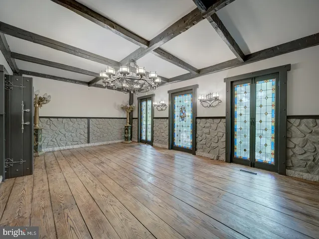 a view of an empty room with wooden floor and a fireplace
