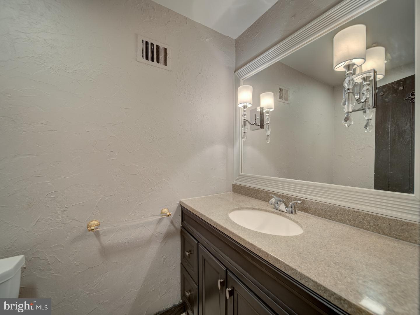2142 Cathedral Avenue Northwest Washington, DC 20008 - Photo 25 of 60 a bathroom with a granite countertop sink a toilet and a mirror