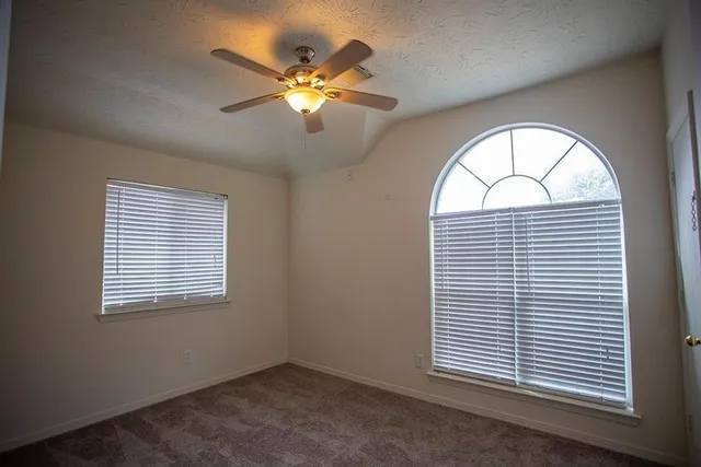 an empty room with windows and chandelier fan