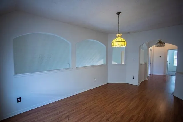 a view of empty room with window and wooden floor