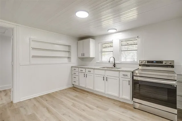 a kitchen with granite countertop a stove cabinets and wooden floor
