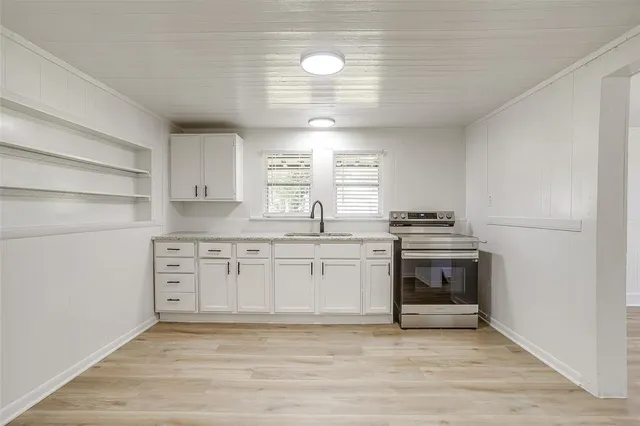 a kitchen with granite countertop a sink cabinets stainless steel appliances and a window