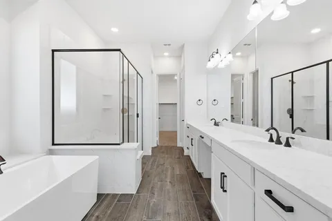 a spacious bathroom with a double vanity sink a mirror a bathtub and shower
