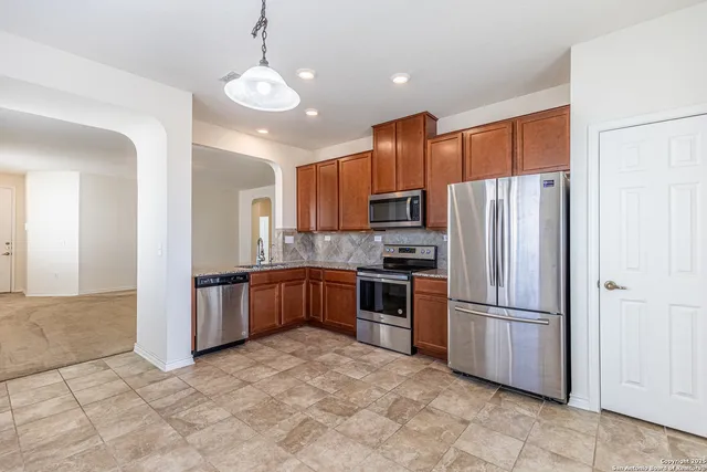 a kitchen with granite countertop a refrigerator and a stove top oven