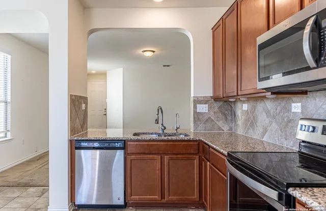 a kitchen with granite countertop a sink stove and microwave