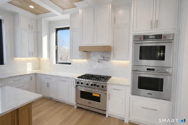 a kitchen with cabinets stainless steel appliances and wooden floor