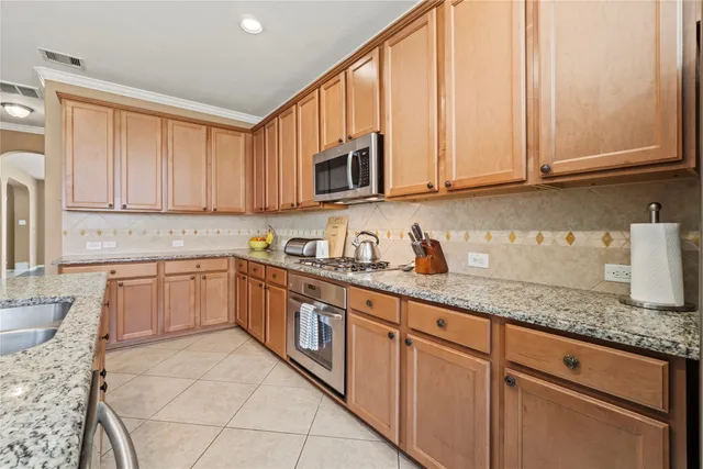 a kitchen with granite countertop white cabinets and stainless steel appliances