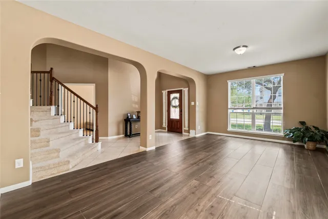 a view of a room wooden floor staircase and windows