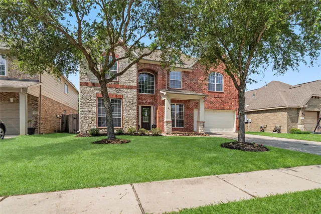 a view of a brick house with a big yard and large trees