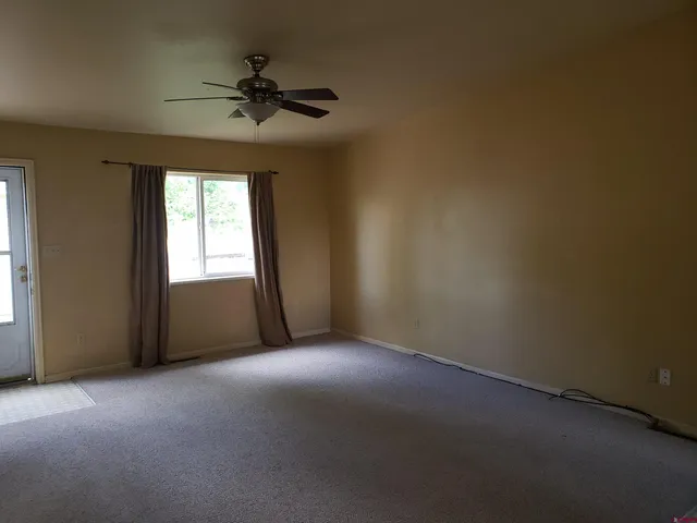 an empty room with a window and a ceiling fan