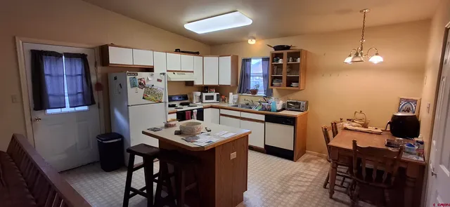 a kitchen with a refrigerator a stove a sink dishwasher a dining table and chairs with wooden floor