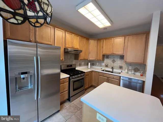a kitchen with stainless steel appliances granite countertop a refrigerator a sink a stove and white cabinets