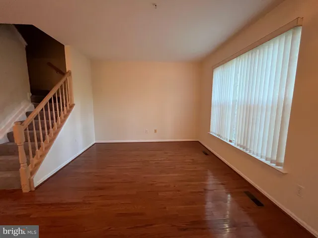a view of an empty room with wooden floor and windows