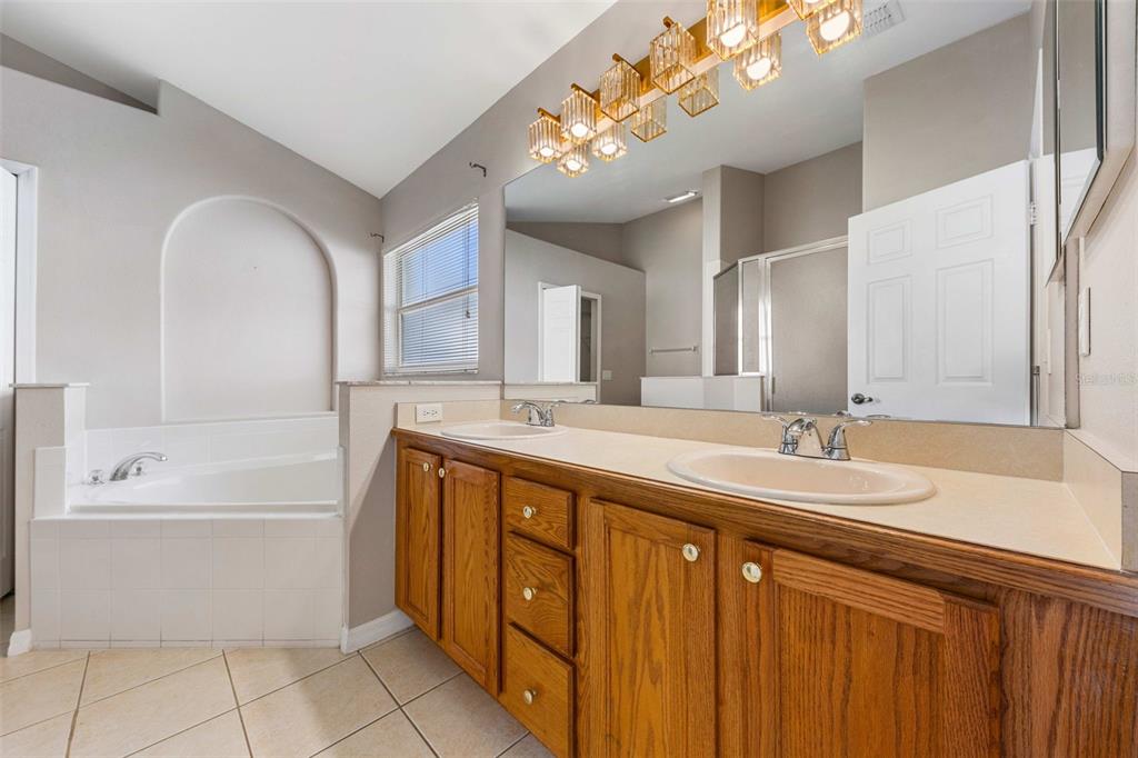 2627 Oneida Loop Kissimmee, FL 34747 - Photo 16 of 32 a spacious bathroom with a sink a large mirror and a bathtub