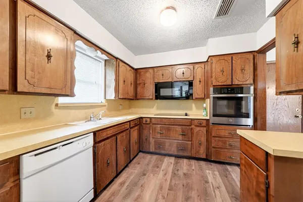 a kitchen with stainless steel appliances a sink cabinets and a wooden floor