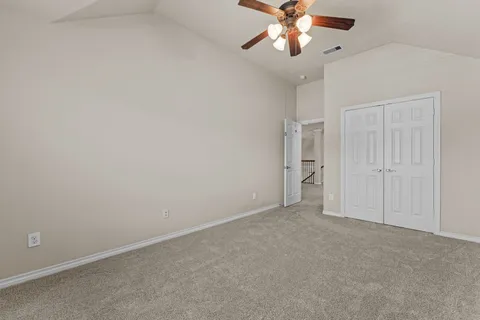 an empty room with a chandelier fan and windows